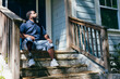 © Creative Flame - Black man with prosthetic leg sitting at front porch of new home purchase