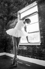 Black Ballerina Doing Powerful Ballet Dance Pose, Wearing Pointe Shoes And White Tutu