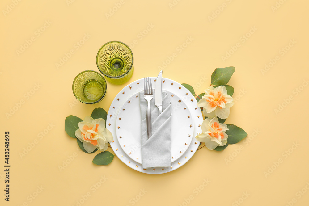 Beautiful table setting with narcissus flowers on color background