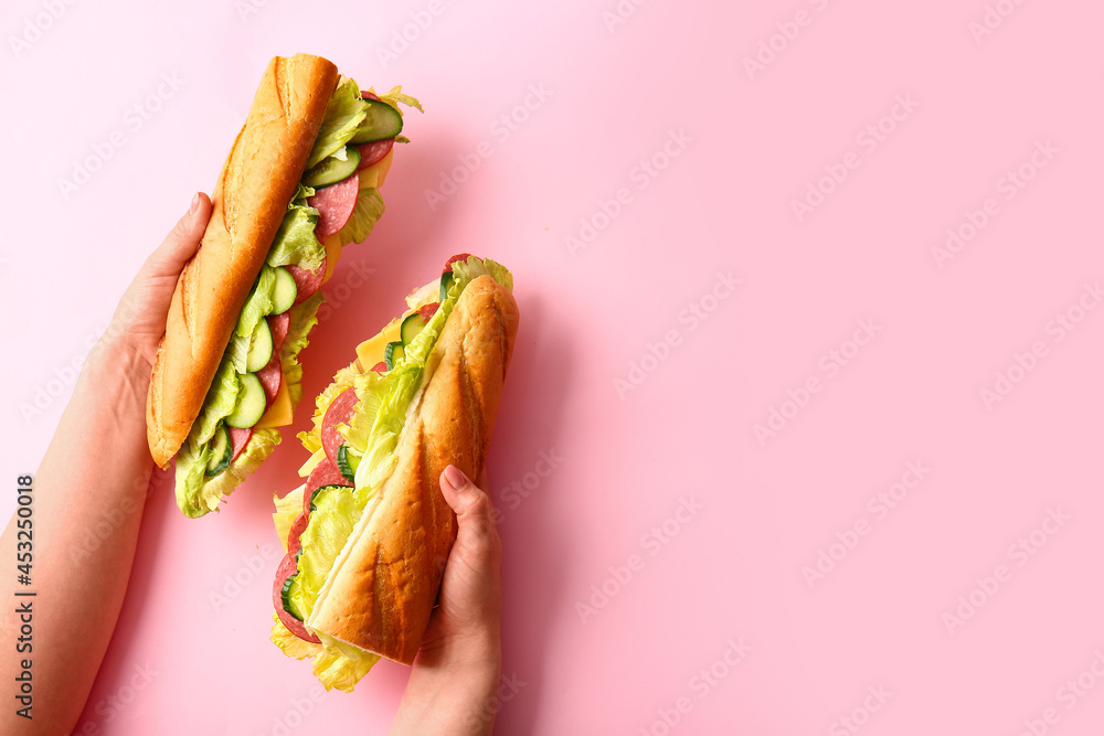 Female hands with tasty sandwiches on color background