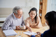 © DragonImages - Real estate manager explaining senior couple how to fill sale deed form