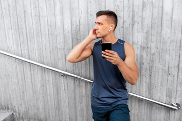 Poster - fitness, sport and technology concept - young athlete man with earphones and smartphone listening to music outdoors