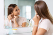 © Syda Productions - beauty, hygiene and people concept - teenage girl with diamond earring looking in mirror at bathroom