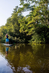  middle aged man paddle boarding on a river