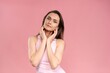 © Svyatoslav Lypynskyy - Touching her chin beautiful young woman with no makeup, skin care concept, attractive brunette girl on pink background. Human emotions, facial expression concept. Beauty concept.