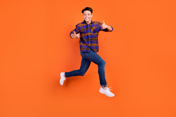 Poster - Full size profile photo of young cool guy jump show thumb up wear shirt jeans sneakers isolated on orange background