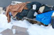 Obdachloser Mann schläfft im Winter auf einer Sitzbank