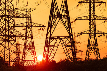 Silhouette of voltage constructions at sunset. Electrical engineering supply shadows.