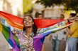 © Drobot Dean - Black woman smiling and holding rainbow flag during pride parade