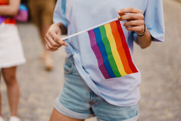 White woman holding rainbow flag during pride parade at street