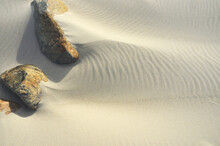 Closeup Shot Of Two Rocks In Seashore Sand Under The Sunlight