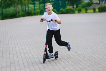 Canvas Print - a young boy riding a scooter in the summer