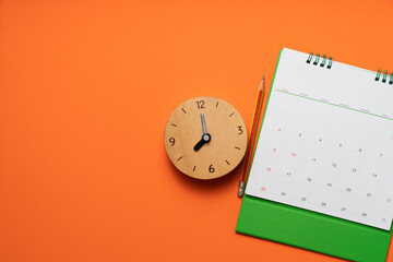 close up of calendar and clock on the orange table background, planning for business meeting or travel planning concept