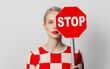 Beautiful woman with blond hair in in a 70s red square dress with stop sign