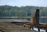 Fototapeta  - Opuszczone stanowisko wędkarskie nad jeziorem. Fotel wyciosany z pnia drzewa i widełki, podpórki na wędki