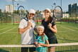 © Peakstock - Sporty family playing tennis. Happy tennis family posing on green tennis court outdoor with rackets