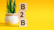 b2b concept with wooden blocks on table, yellow background