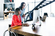 © Marcos - Mexican transgender woman sitting in wheelchair and office colleagues working on project using computer in office in Latin America