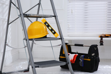 Poster - Metal stepladder with hardhat, level and toolkit indoors