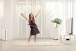 Playful schoolgirl dancing with a hula hoop at home