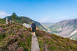 Man hiking on a boardwalk up the hill on the Spinc trail, overlooking the Glenealo Valley, in Wicklow Mountains, Ireland.
