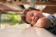 © Mahsun - Cute happy  little boy lying at the table with head in his hands and looking at the camera.