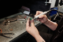Close-up Of Unrecognizable Bench Jeweler With Dirty Hands Polishing Inner Part Of Ring On Work Station