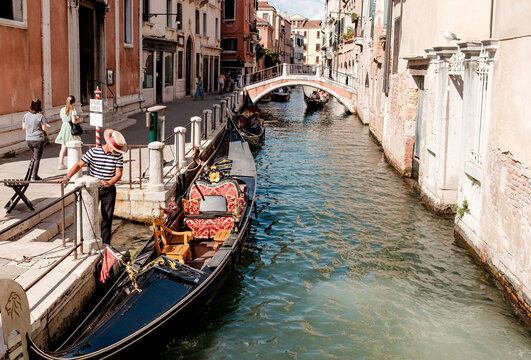 Fototapete - Gondolier at his boat in a canal in Venice/Italy