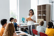 © LIGHTFIELD STUDIOS - cheerful african american teacher holding book near multiethnic schoolkids