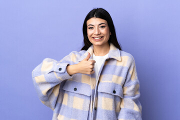 Wall Mural - Young brunette woman over isolated purple background giving a thumbs up gesture