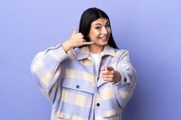 Wall Mural - Young brunette woman over isolated purple background making phone gesture and pointing front