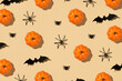 © ActionGP - Happy Halloween concept. Overhead close up view photo of pattern of orange funny pumpkin spiders and bat isolated bright color beige background