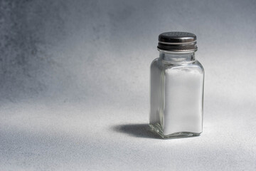 A pile of salt from salt shaker, concept excessive salt intake and white death