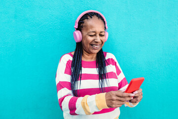 Wall Mural - African senior woman listening music on mobile phone app - Focus on face