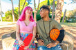 © blackandbrightph - alternative diverse couple hanging out together chilling and smiling sitting in a park holding a basketball and skateboard. happy interracial friends laughing outdoors. joy, fun and lifestyle concept