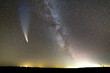 Night landscape of dark hill with stars covered sky and Neowise comet with light tail.