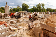 Construction Site With Piles Of Sand And Concrete Car Mixers