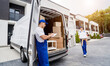 © romaset - Two removal company workers are loading boxes and furniture into a minibus.