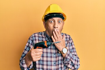 Poster - Handsome senior man with grey hair holding screwdriver wearing hardhat covering mouth with hand, shocked and afraid for mistake. surprised expression