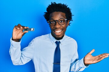 Sticker - Young african american man holding ssd memory celebrating achievement with happy smile and winner expression with raised hand