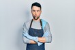 © Krakenimages.com - Young hispanic man wearing apron with arms crossed making fish face with mouth and squinting eyes, crazy and comical.