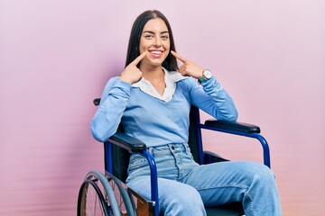 Poster - Beautiful woman with blue eyes sitting on wheelchair smiling with open mouth, fingers pointing and forcing cheerful smile