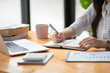 © Songsak C - Female hands with pen writing on notebook.