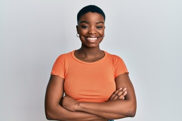 Wall Mural - Young african american woman wearing casual orange t shirt happy face smiling with crossed arms looking at the camera. positive person.