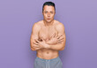 © Krakenimages.com - Handsome young man wearing swimwear shirtless shaking and freezing for winter cold with sad and shock expression on face