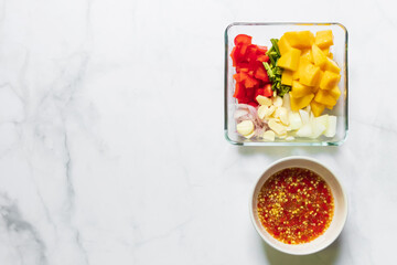 Wall Mural - Ripe mango, bell pepper, culantro garlic, onion and spicy sauce on table top view and copy space. Ingredient for delicious mango spicy salad.