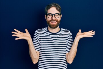 Wall Mural - Caucasian man with beard wearing striped t shirt and glasses celebrating crazy and amazed for success with arms raised and open eyes screaming excited. winner concept