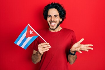 Sticker - Handsome hispanic man holding cuba flag celebrating achievement with happy smile and winner expression with raised hand