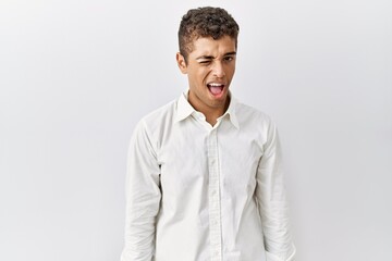 Poster - Young handsome hispanic man standing over isolated background winking looking at the camera with sexy expression, cheerful and happy face.