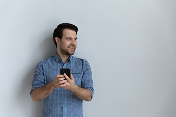 Wall Mural - isolated portrait of happy millennial user in casual holding mobile phone, looking at copy space awa